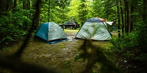 two camping tents and car in woods